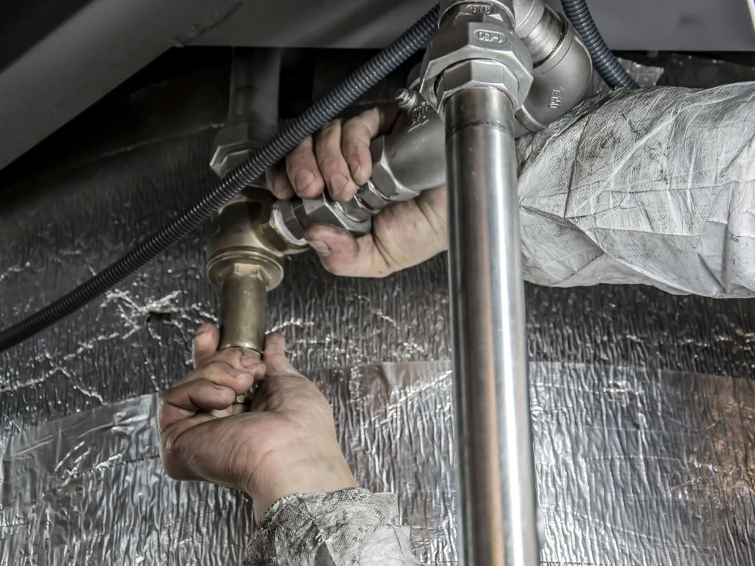 A tradesperson's hands working on a steel pipe joint.